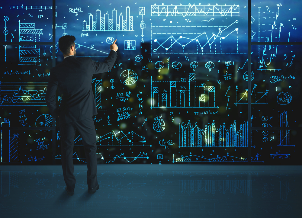 Businessman drawing business statistics on glass wall