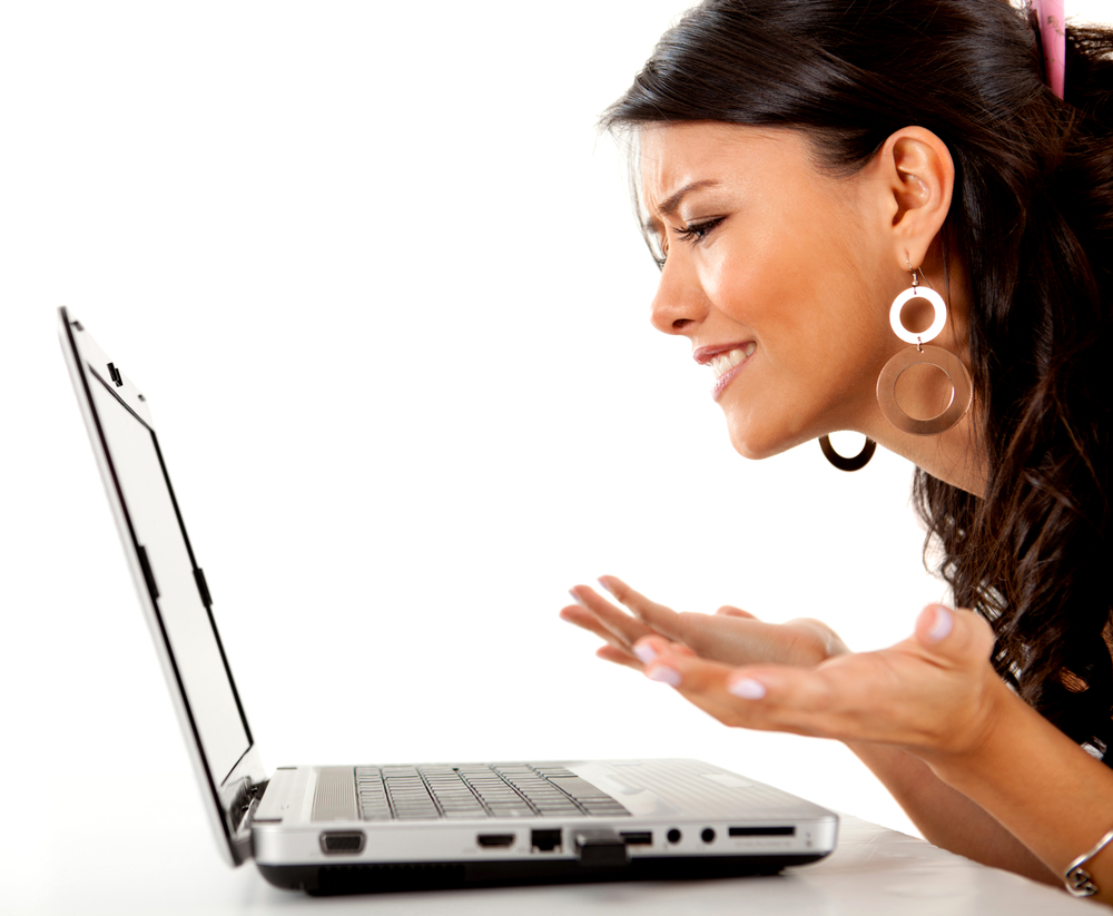 Confused woman working on a laptop computer - isolated over white
