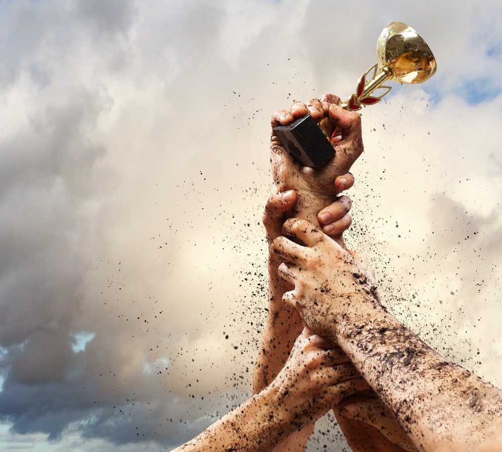 Hands squeeze the cup winner against lightning dark sky.